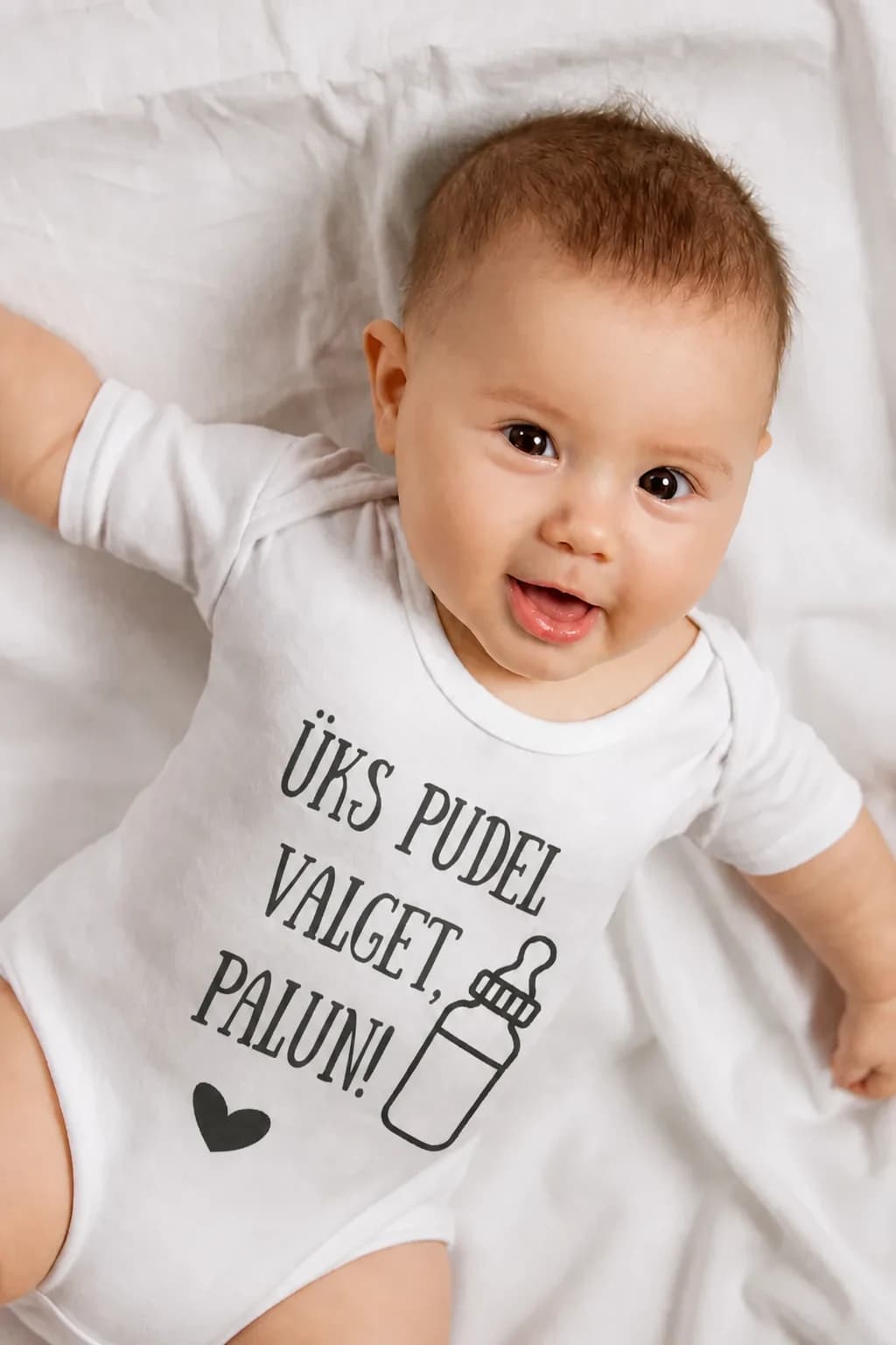 Valge naljakas beebibodi lutipudeli ja kirjaga „Üks pudel valget, palun!“, beebi lamab voodil