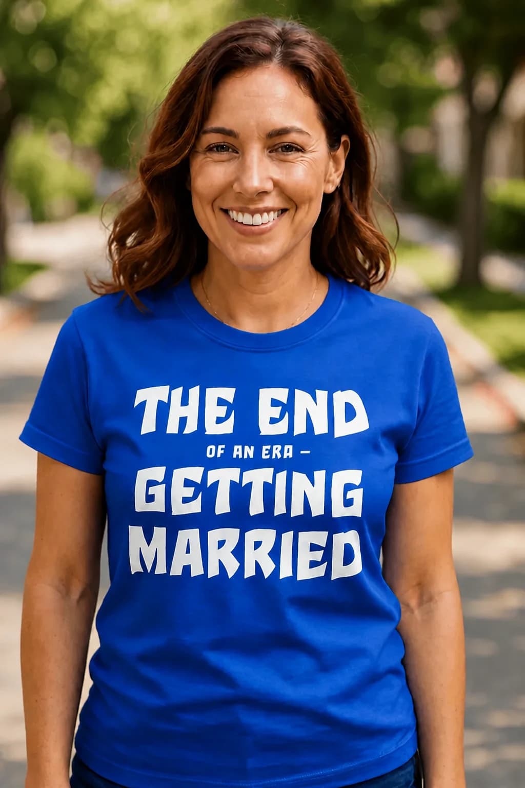 Kuningasinine T-särk poissmeesteõhtuks valge kirjaga „The end of an era – getting married“ naise seljas