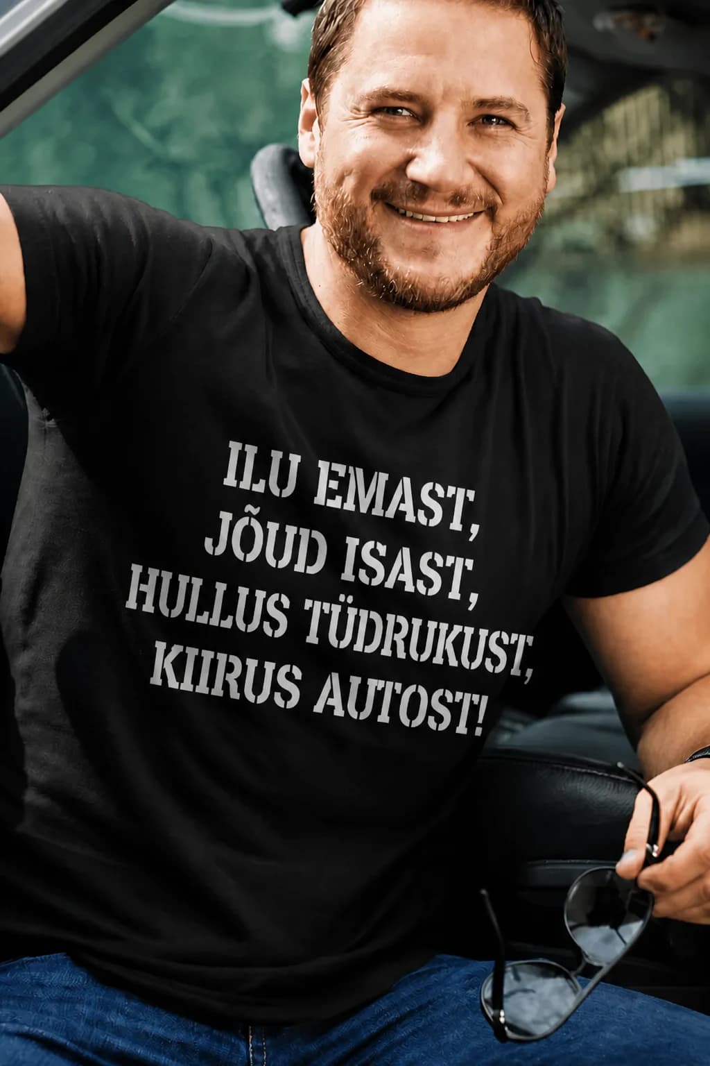 Naeratav mees mustas T-särgis kirjaga Ilu emast, jõud isast, hullus tüdrukust, kiirus autost – T-särk autohuvilisele