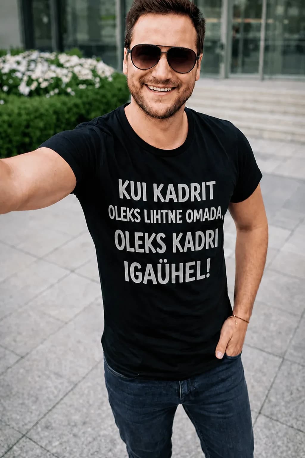 Mees mustas T-särgis valge kirjaga „Kui Kadrit oleks lihtne omada, oleks Kadri igaühel!“ – särk soovitud nimega