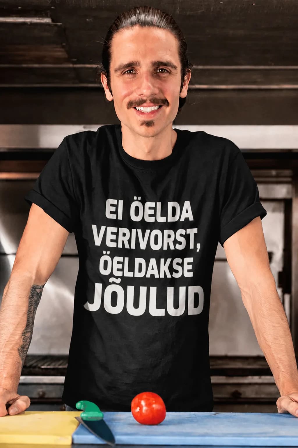 Naeratav mees köögis mustas T-särgis suure valge kirjaga – naljakas T-särk kokale ja toidusõbrale