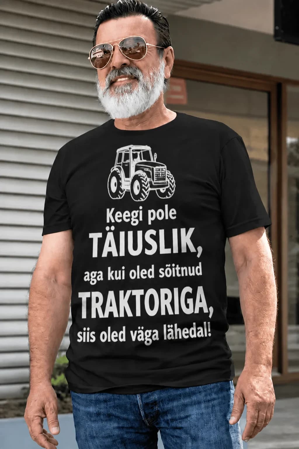 Eakas mees päikeseprillides mustas T-särgis, kiri „Keegi pole täiuslik, aga kui oled sõitnud…“ ja auto joonis